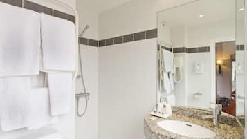 A bathroom with a white sink, a mirror, and a shower.