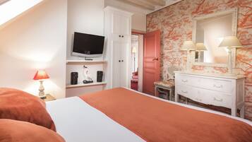 A bedroom with a bed, a television, a dresser, and a mirror.