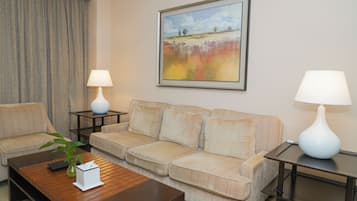 Una sala de estar con un sofá color beige, dos lámparas blancas, un cuadro enmarcado y una mesa de centro con una planta.