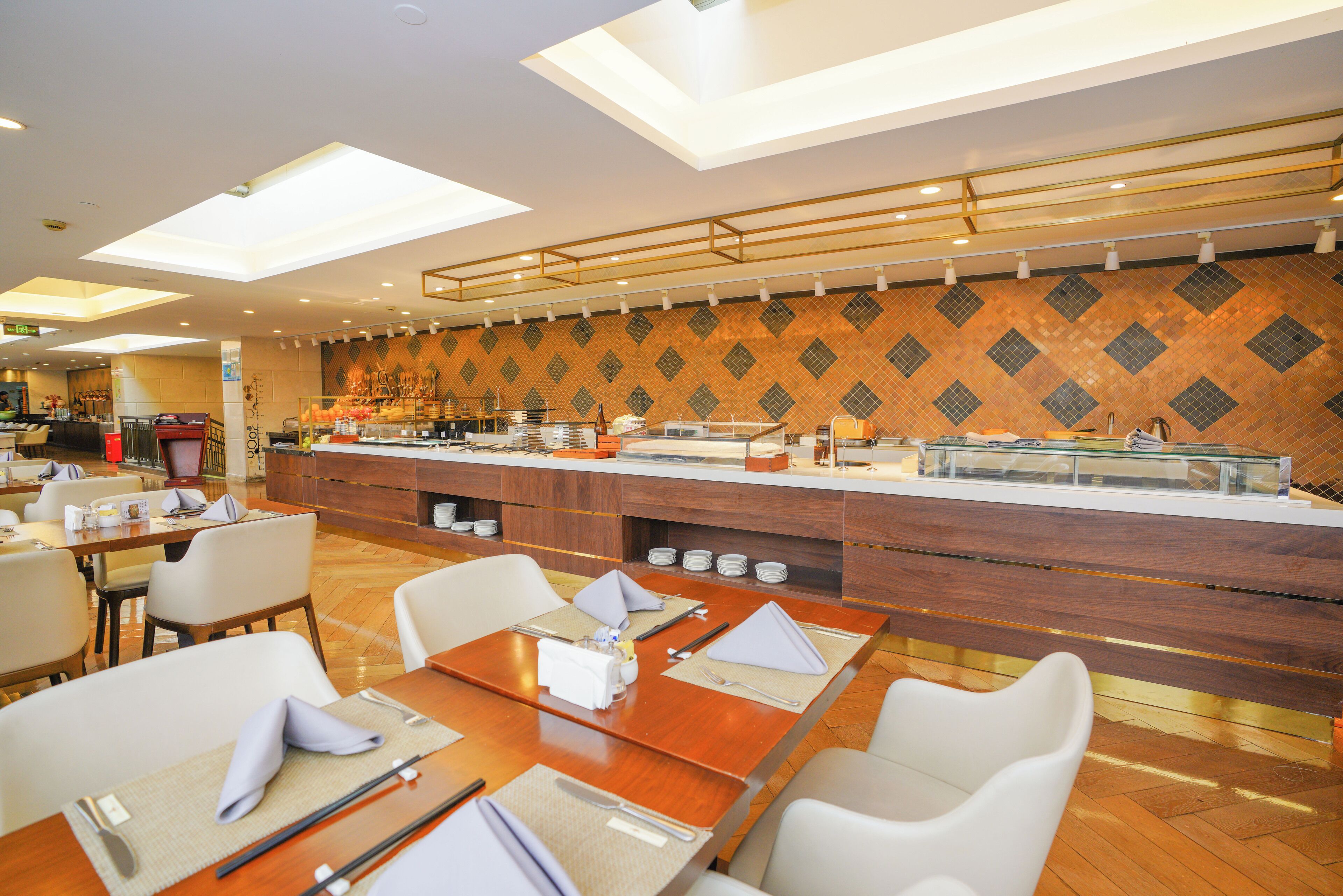 A modern restaurant with a long counter, multiple dining tables, and chairs.
