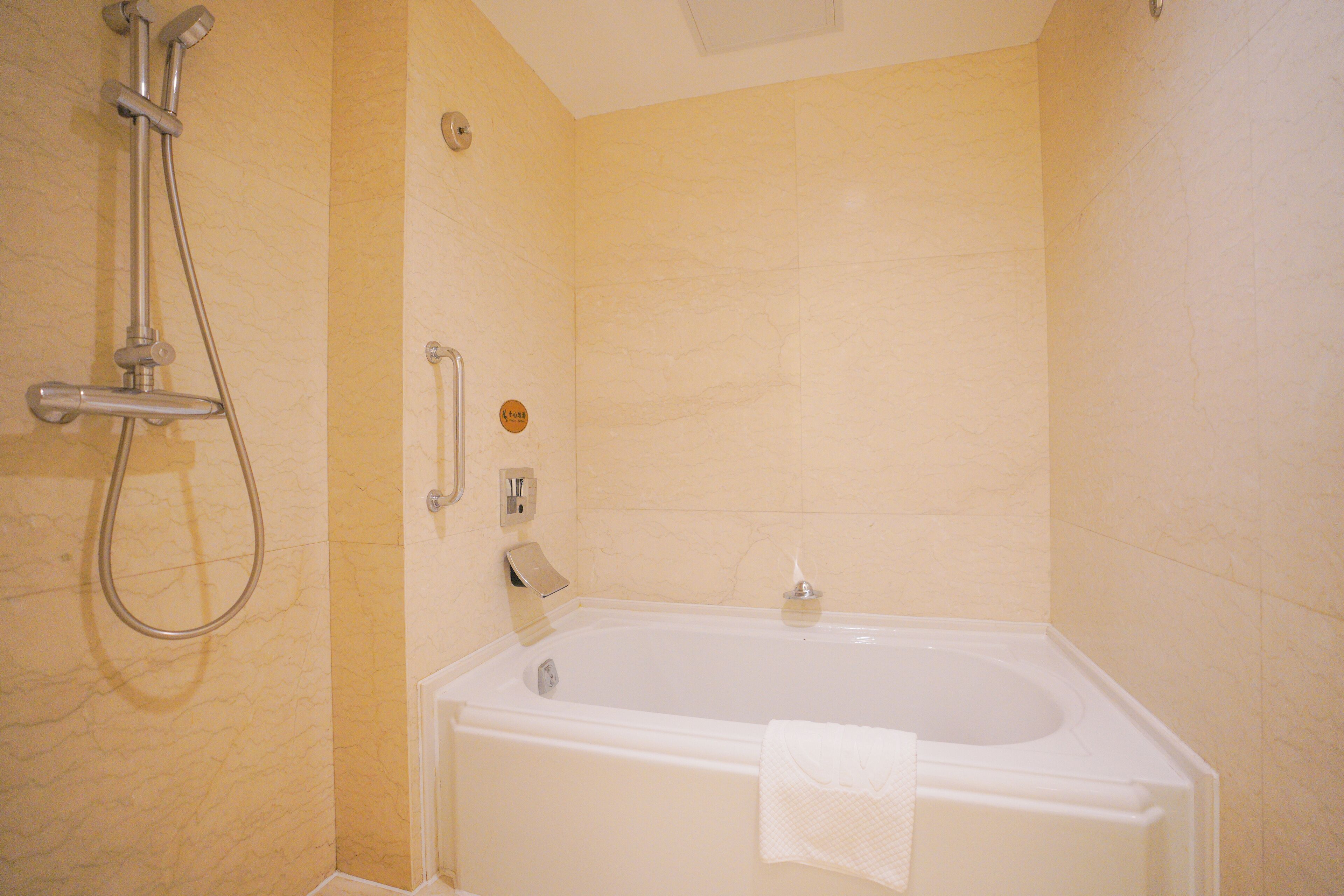 Une salle de bain avec une baignoire, une douche et une serviette accrochée au mur.