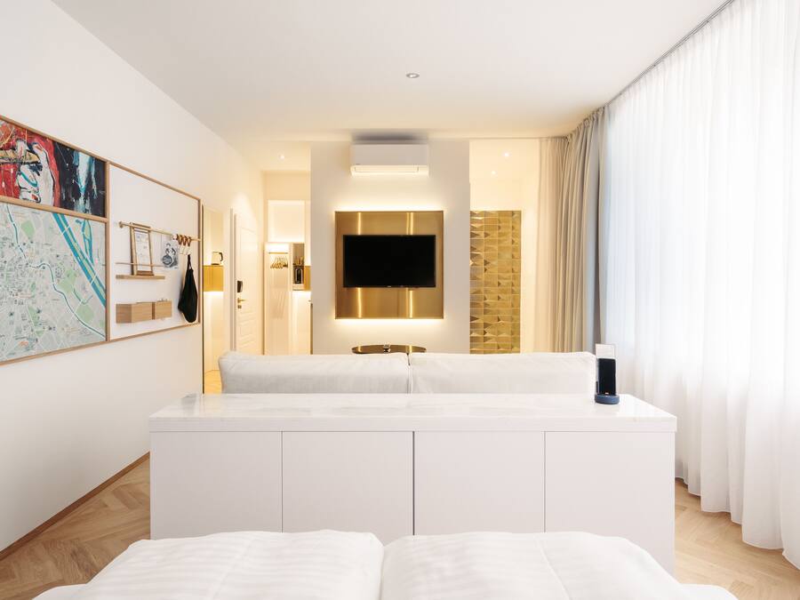 A modern hotel room with a large bed, a flat-screen TV, a map on the wall, and a view of the city.