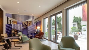 A modern interior with a staircase, seating area, and large windows offering views of the outdoors. - Der Wilhelmshof (Vienna)