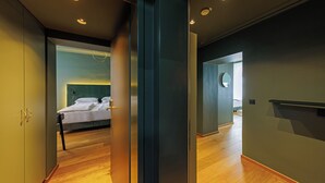 A modern hotel room with a wooden floor, a bed with white linens, and a large mirror on the wall. - Der Wilhelmshof (Vienna)