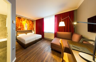 Quarto de hotel com cama, sofá, mesa de jantar e televisão.