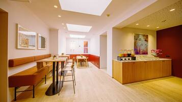Un interior moderno con zona de comedor, cocina y rincón de estar con un banco.