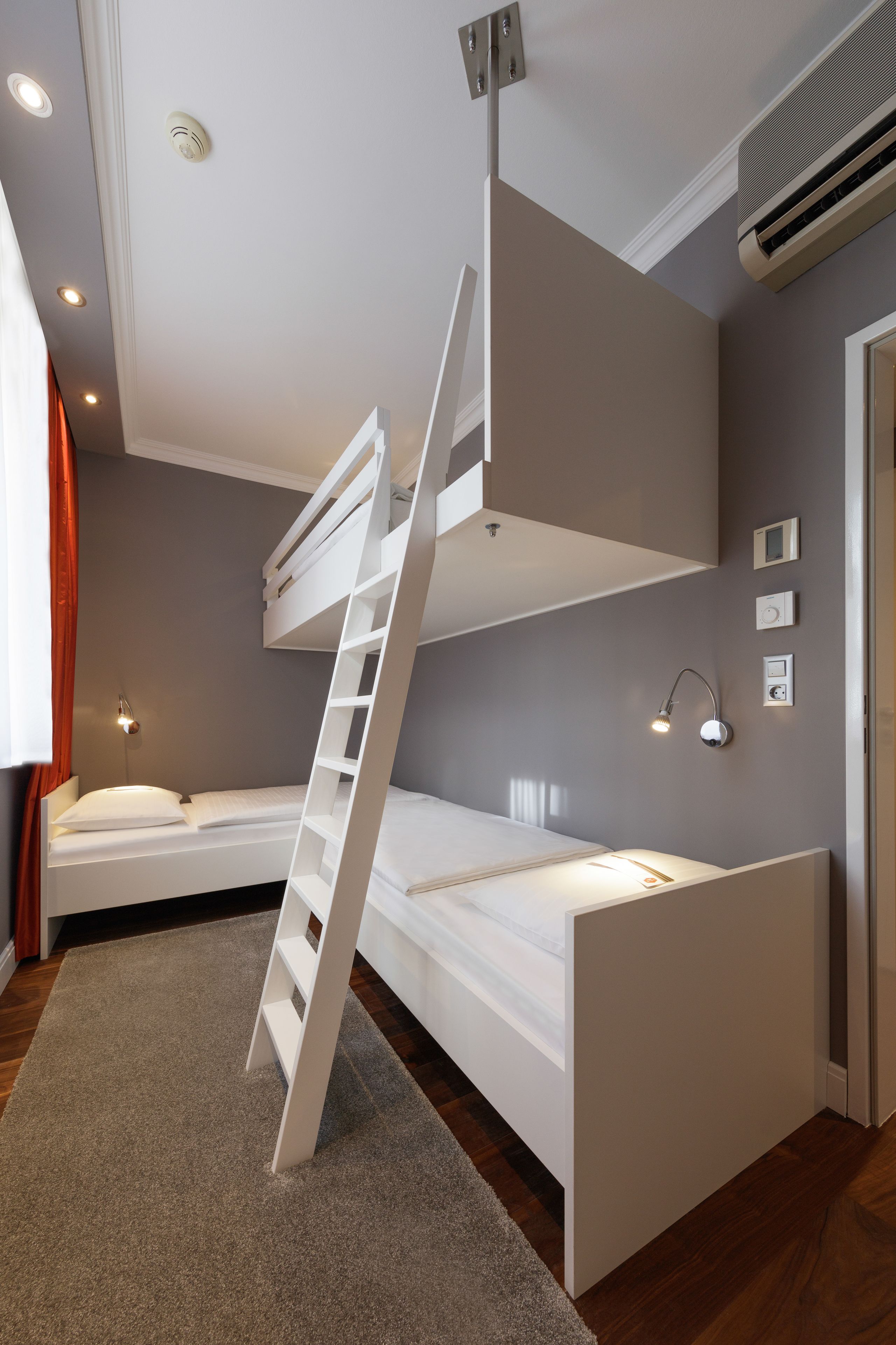 Une chambre avec un lit superposé, une échelle, un bureau et une chaise.