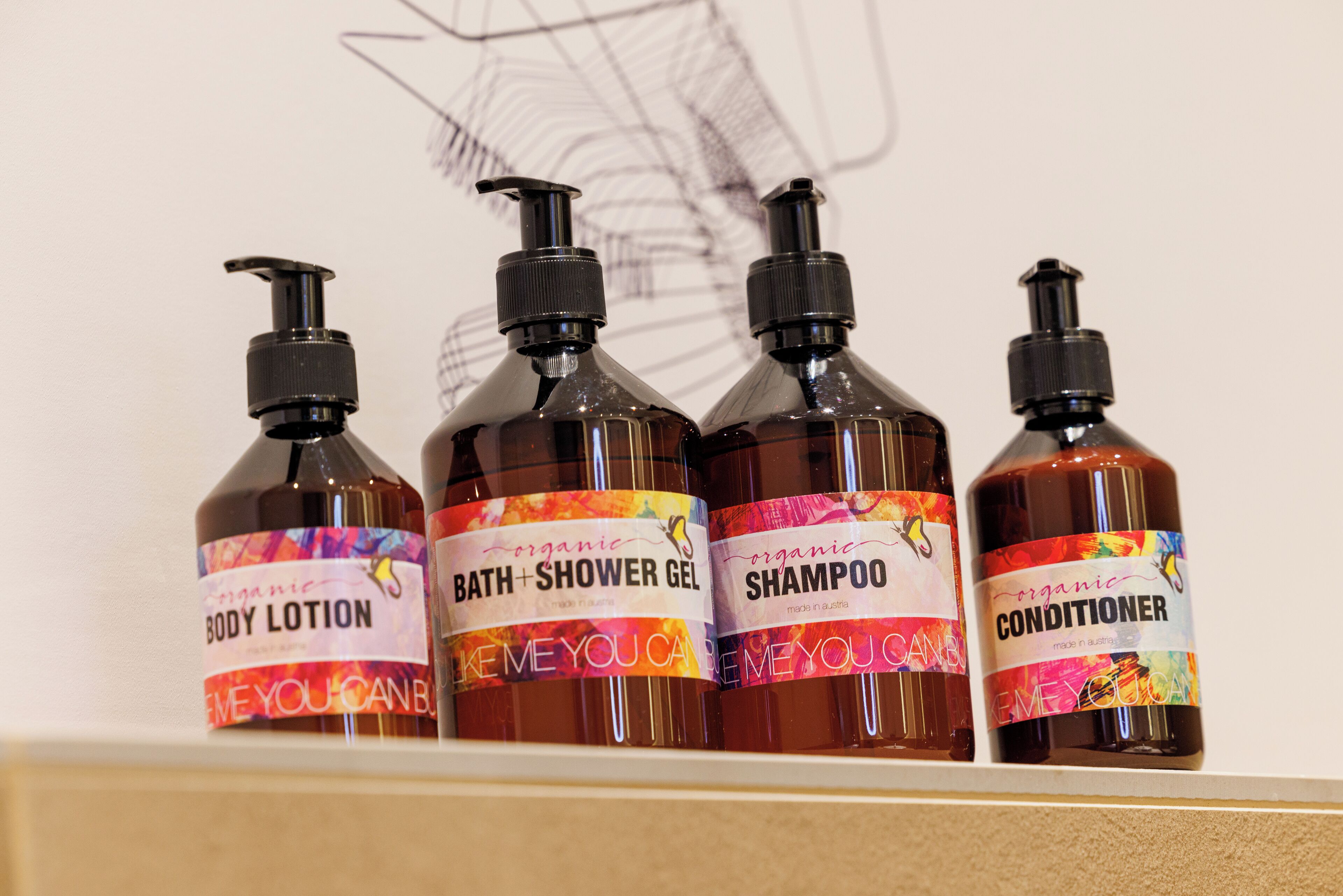 Quatro frascos de produtos orgânicos para o cuidado do corpo em uma prateleira.