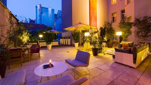An outdoor patio area with seating, tables, and potted plants. - Der Wilhelmshof (Vienna)