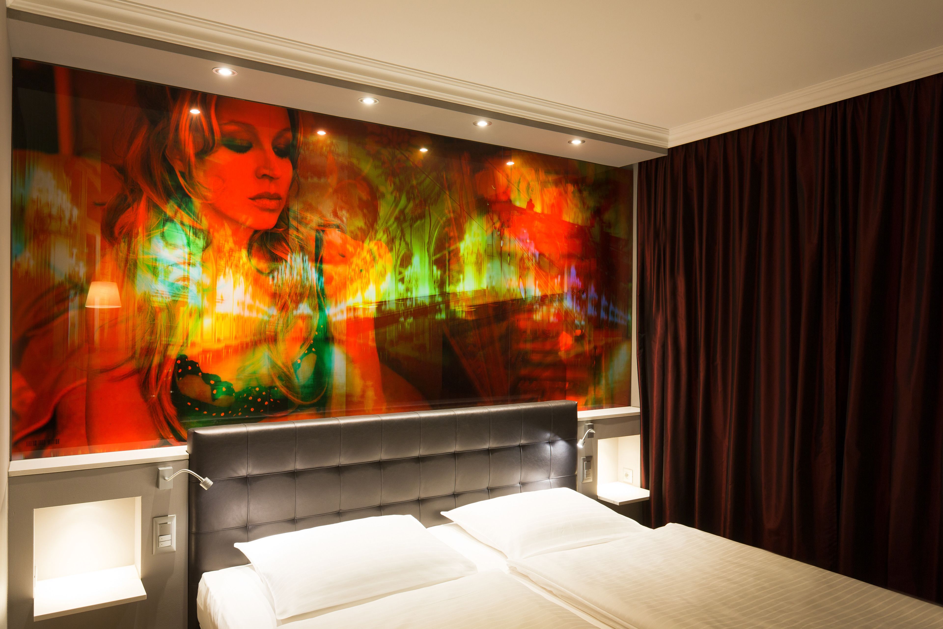 Una habitación de hotel moderna con un cuadro abstracto grande en la pared, un cabecero capitonado y un amplio ventanal con cortinas.
