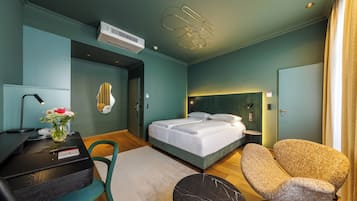 A modern hotel room with a bed, a desk, a chair, and a small table.