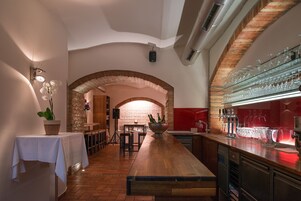 Uma área de bar com um balcão comprido, banquetas e um arco de tijolos.