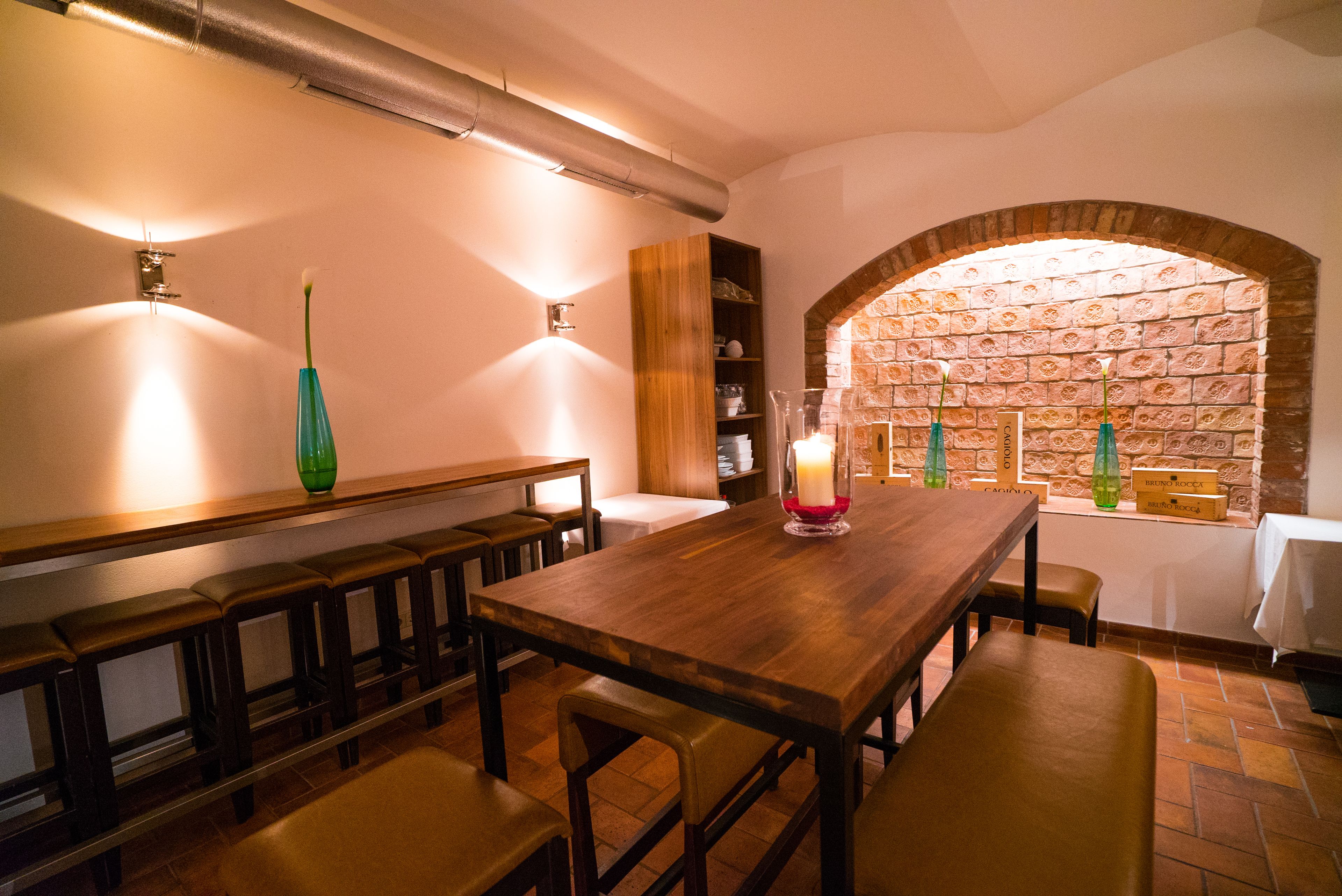 Ein Restaurant mit Holztisch und -bänken, einer Ziegelwand mit Fenster und einem Regal mit Flaschen.