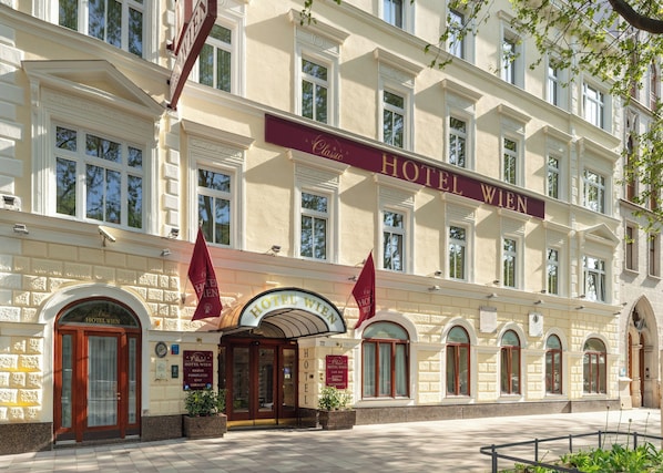 Un edificio clásico con un letrero que dice "Hotel Wien" y una amplia entrada en arco.