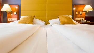 A hotel room with two beds, a large yellow headboard, bedside lamps, and a telephone on the nightstand.
