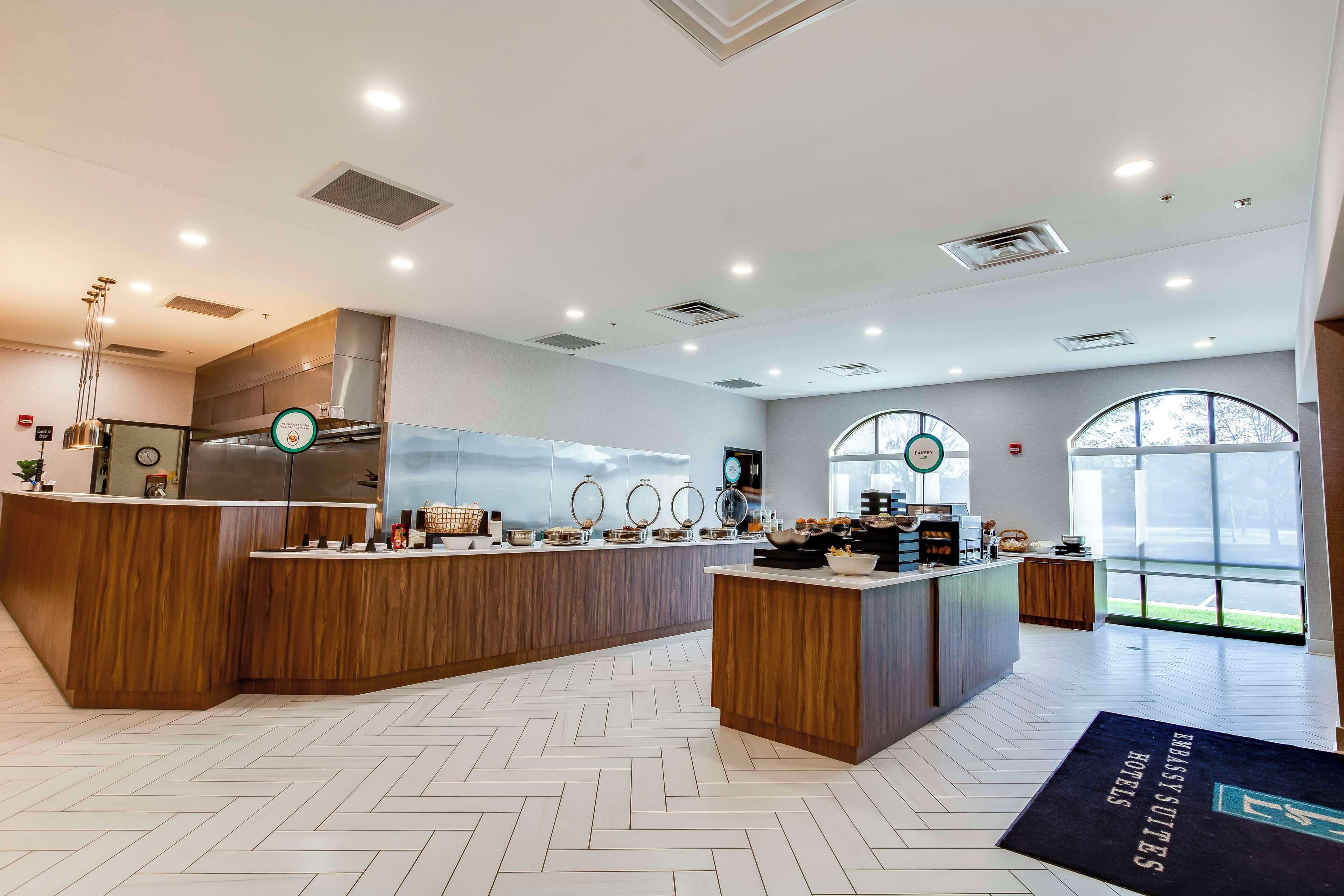 En moderne hotellobby med en træreception, et stort køkkenområde og udsigt til det fri gennem store vinduer.