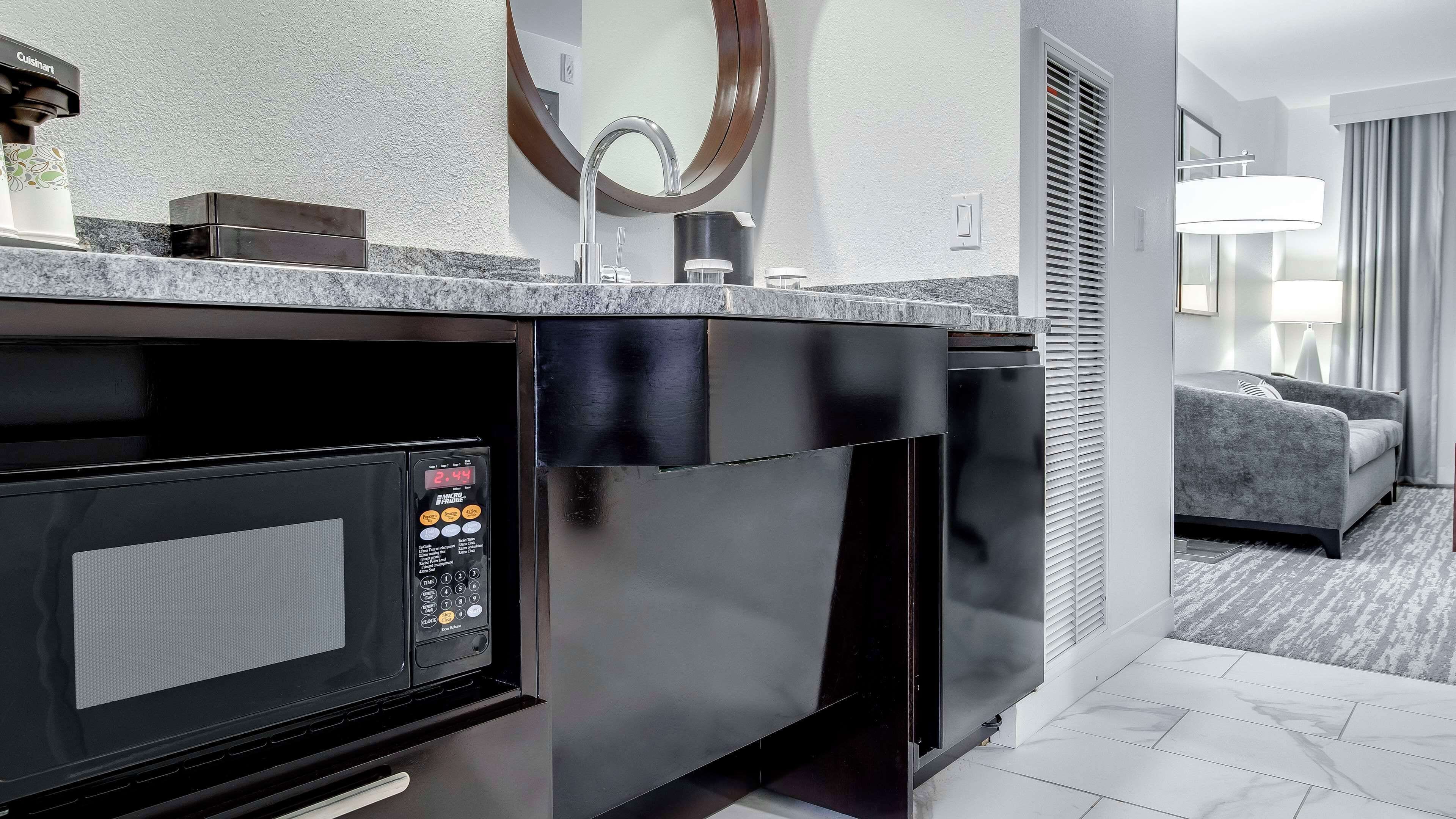 Een moderne keuken met een ingebouwde magnetron, een koffiezetapparaat en een strak aanrecht.