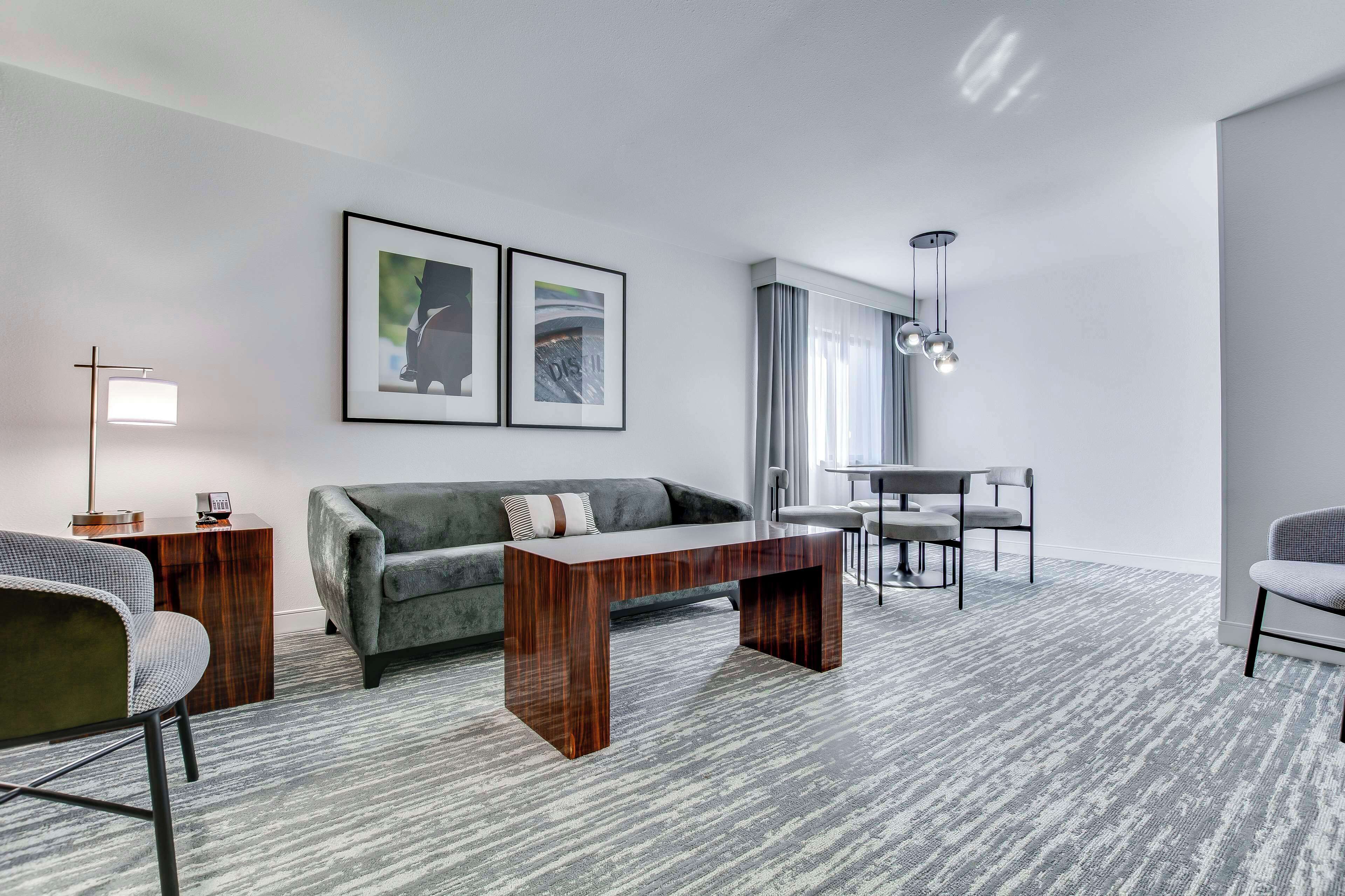 Uma sala de estar moderna com um sofá cinzento, uma mesa de centro de madeira e uma área de jantar com mesa e cadeiras.