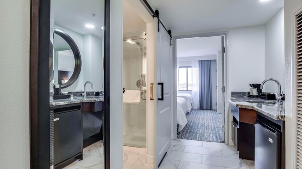 Un baño de hotel con lavamanos, espejo e inodoro ducha.