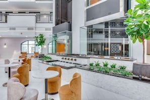 A modern indoor space with seating areas, a central water feature, and a view of the building's interior.