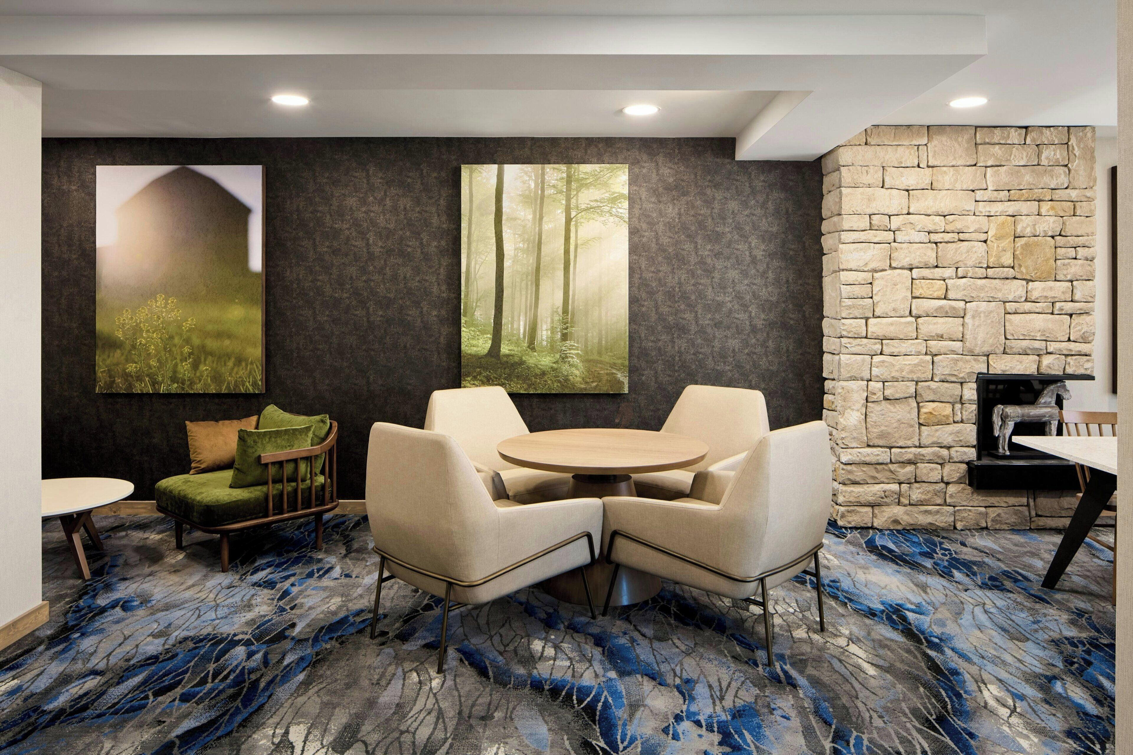 A modern lounge area with a stone wall, a fireplace, and a large forest mural.