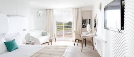 A modern hotel room with a large bed, a desk, and a balcony with a view.