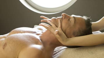 Een persoon ligt op een massagetafel met een handdoek en ontvangt een rugmassage.