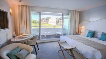 Une chambre d’hôtel avec un lit, un bureau, une chaise et un balcon donnant sur des immeubles.