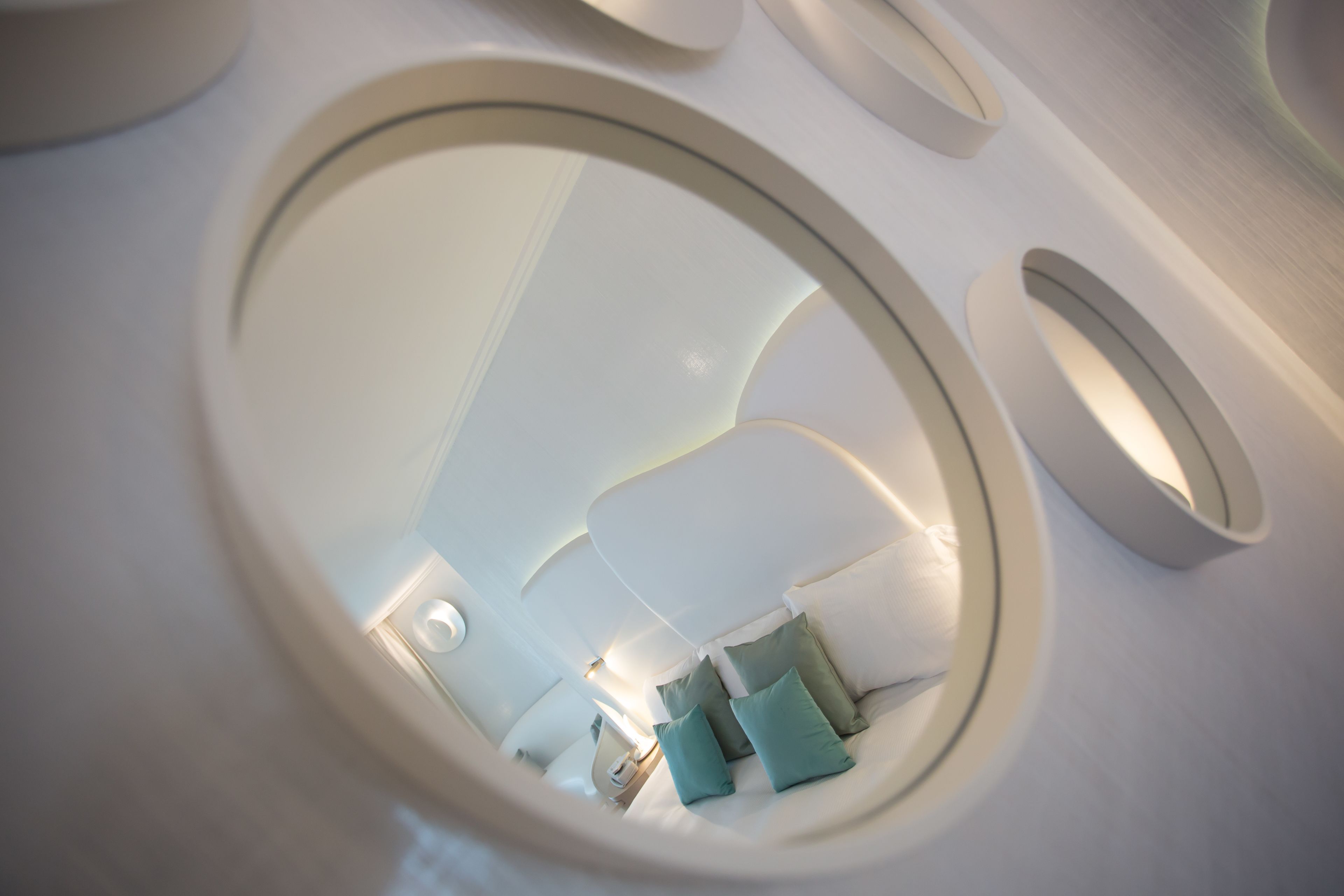 Espejo circular que refleja un interior moderno con un sofá y almohadones.