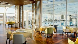 Een restaurant met gedekte tafels, grote ramen en uitzicht over de stad.