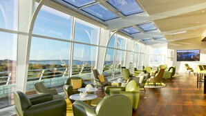 Een moderne lounge met grote ramen, comfortabele zitplaatsen en een flatscreen televisie.