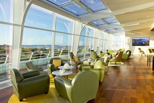 A modern lounge with large windows, comfortable seating, and a flat-screen TV.