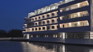 Een meerdekker riviercruiseschip met balkons en grote ramen, afgemeerd in de nacht.