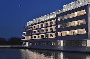 A multi-story riverboat with balconies and large windows, docked at night.