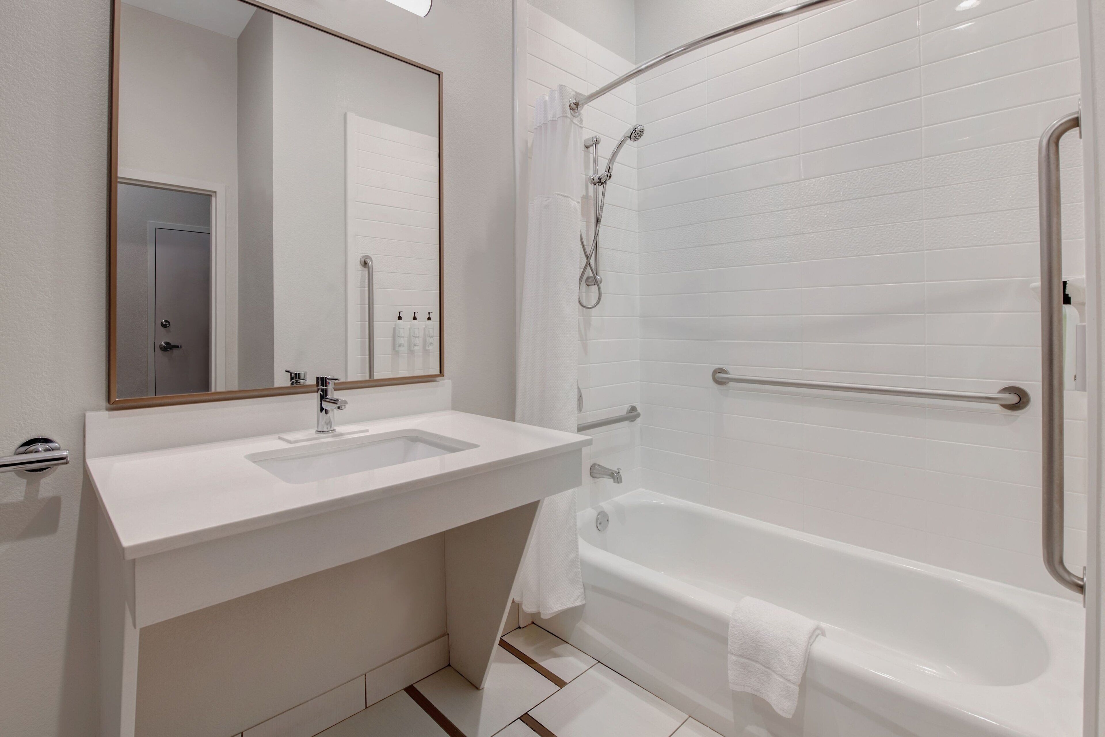 A modern bathroom with a white sink, mirror, and bathtub.