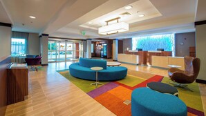A modern lobby with a reception desk, seating area, and a view of the outside.