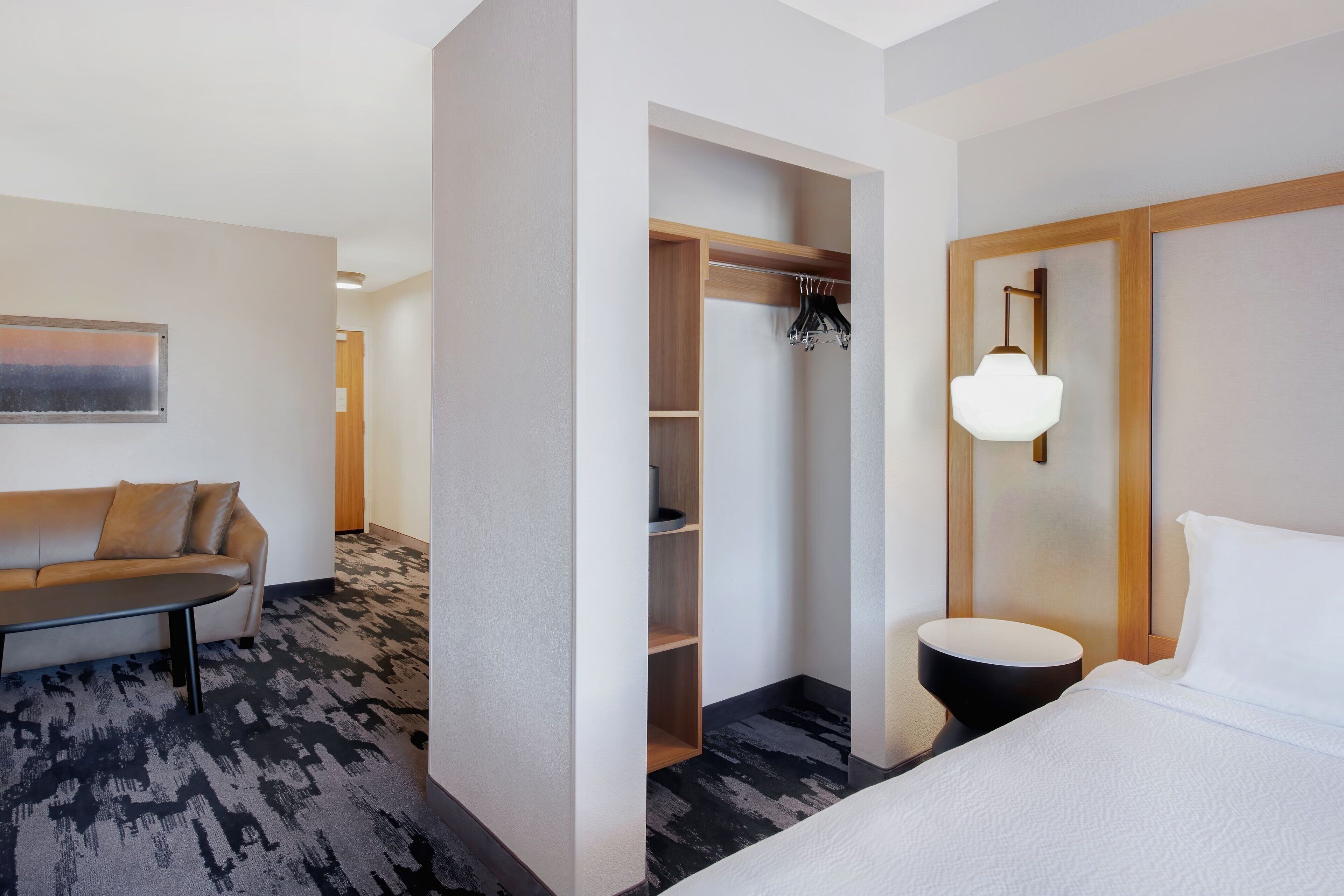 Une chambre d’hôtel comprenant un lit, un coin salon avec un canapé, une armoire et un luminaire fixé au mur.