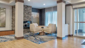 A modern interior with a stone accent wall, a round table with chairs, and a view through a glass door.