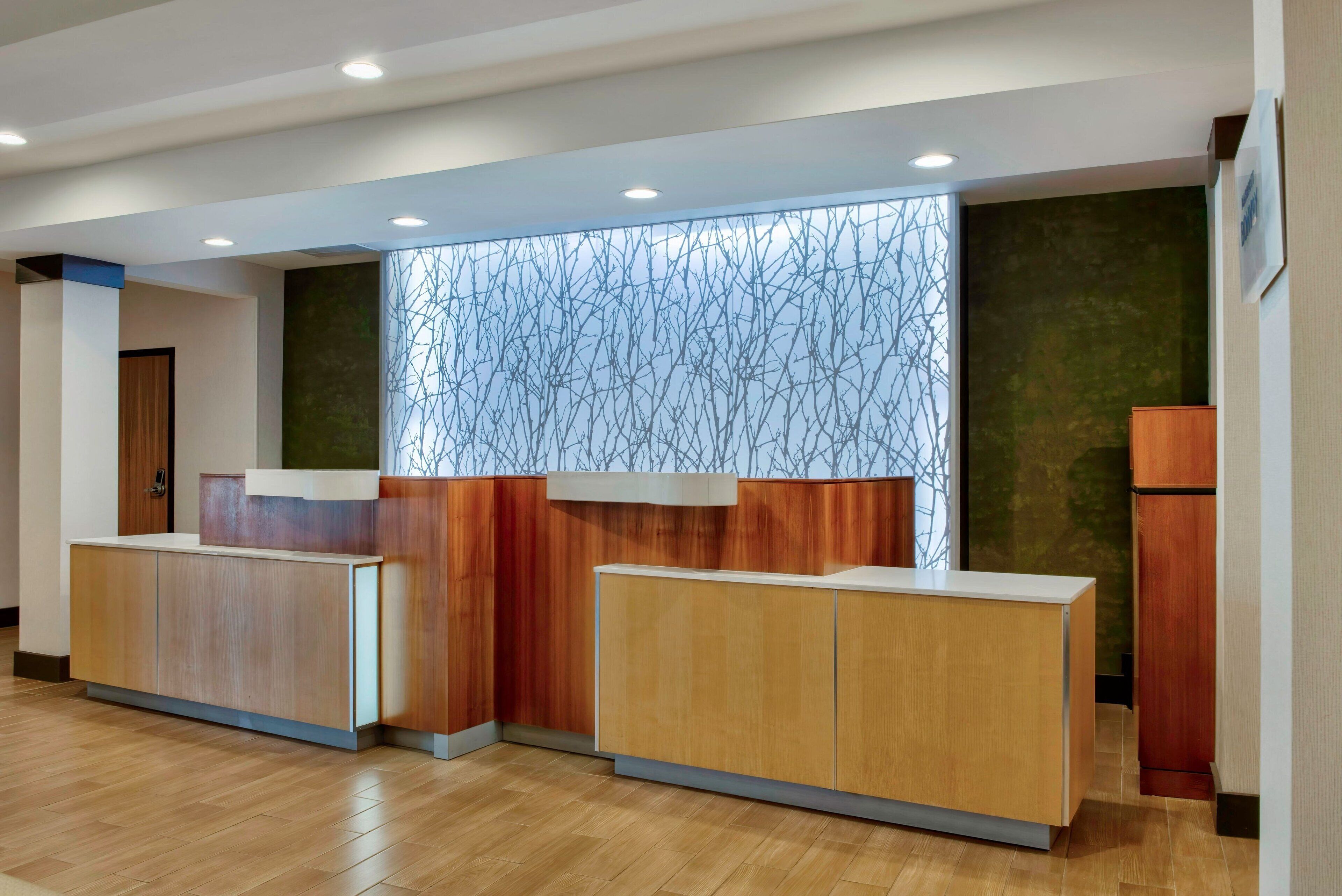 Zona de recepción con mostradores de madera, pared con diseño y una puerta.