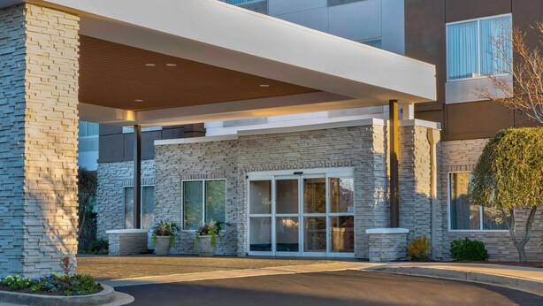 A modern building with a stone facade, large windows, and a covered entrance area.