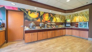 A breakfast area with a wooden counter, a coffee machine, and a fruit display.