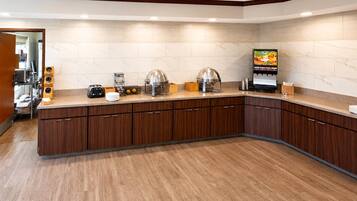 A modern kitchen with a marble backsplash, wooden cabinets, and a built-in coffee machine.