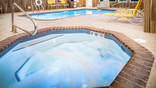 An indoor swimming pool with a 3ft depth marker, lounge chairs, and a changing room area.