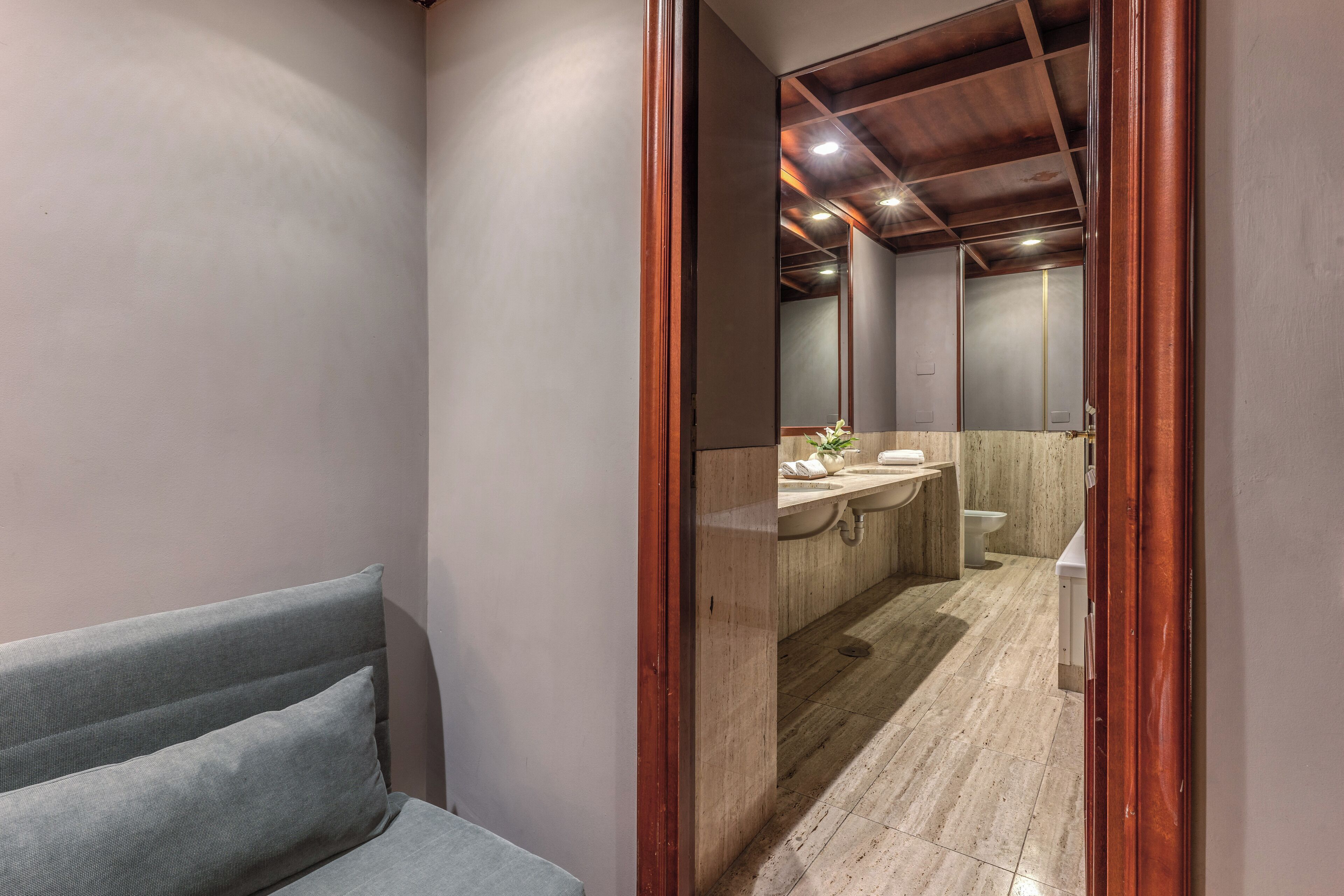 Un bagno moderno con soffitto in legno, lavabo in marmo e un water.