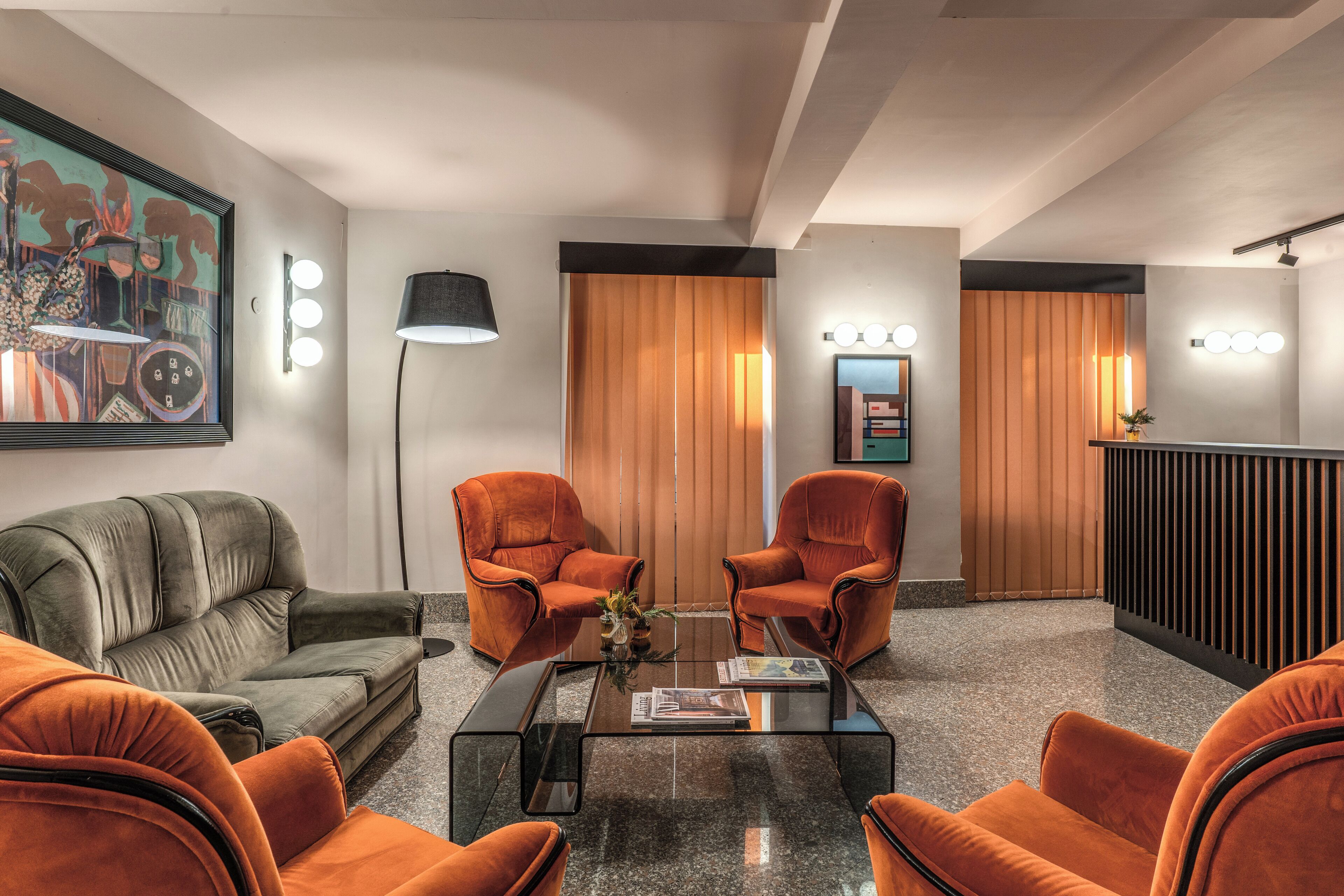A modern lobby with a sofa, two armchairs, a glass coffee table, and a reception desk.