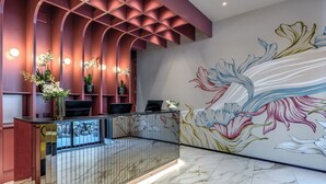 A reception area with a marble floor, a reception desk, and a wall with a floral mural.