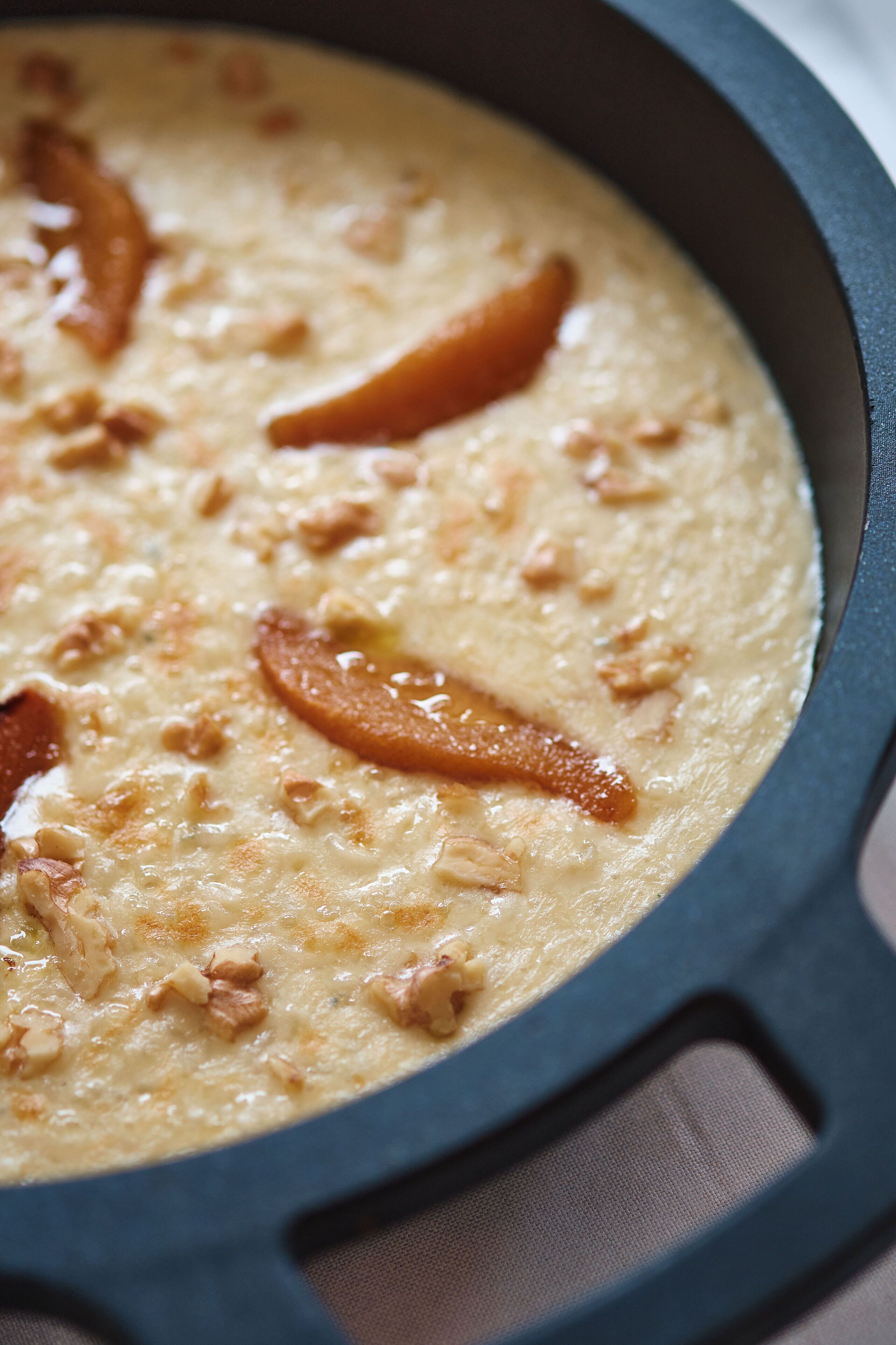 A close-up of a creamy dish in a cast iron skillet with visible chunks of meat and caramelized onions.