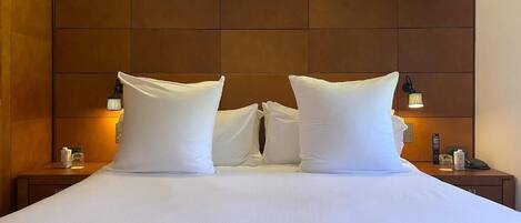 Une chambre d’hôtel avec un grand lit, deux tables de chevet et une tête de lit.