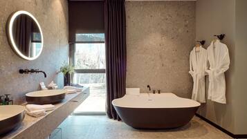 A modern bathroom with two sinks, a large bathtub, and a mirror.