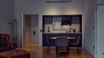 A modern kitchen with a dining area, featuring a round table and chairs, a sofa, and a coffee machine.